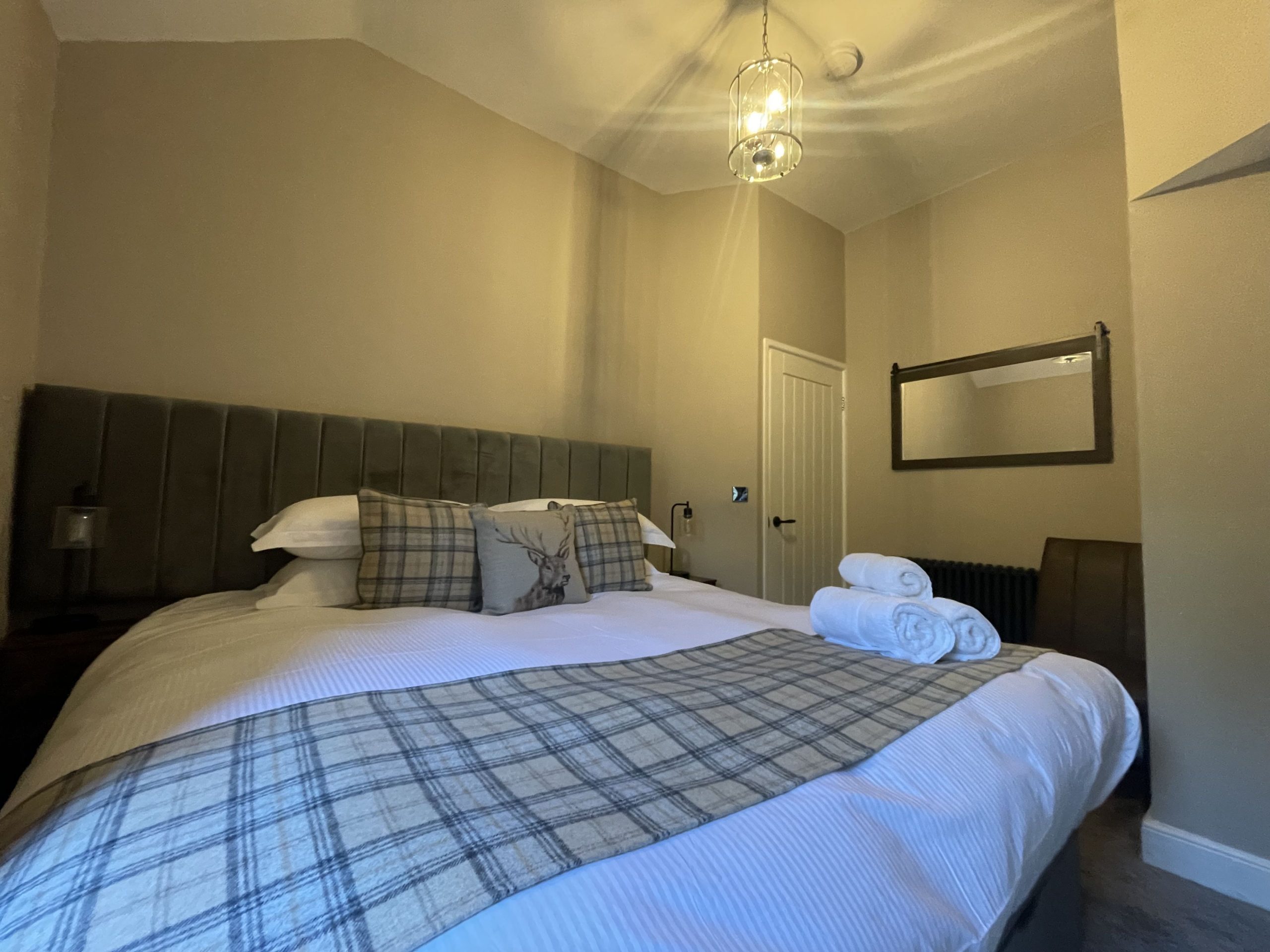 The bedroom is furnished with a double bed, bedside tables and lights, and clothing rails.