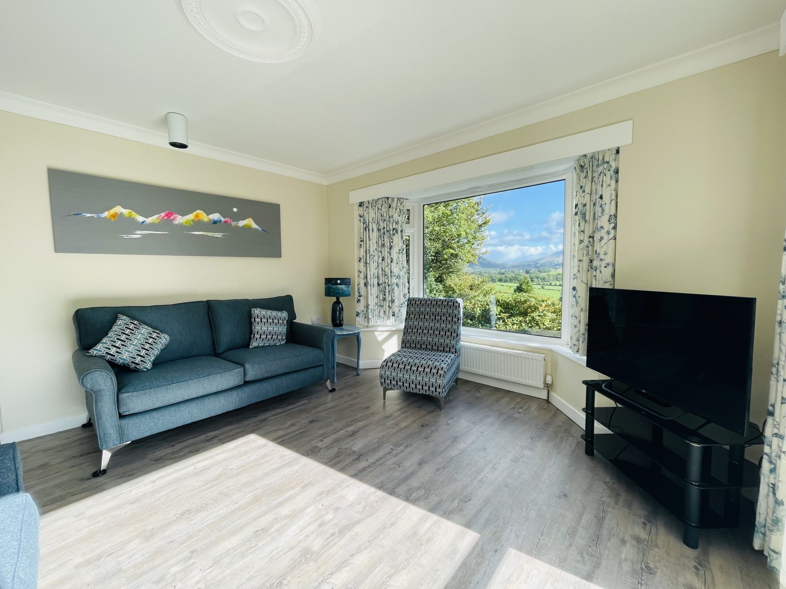 The living room is spacious and features a large picture window with views over the valley