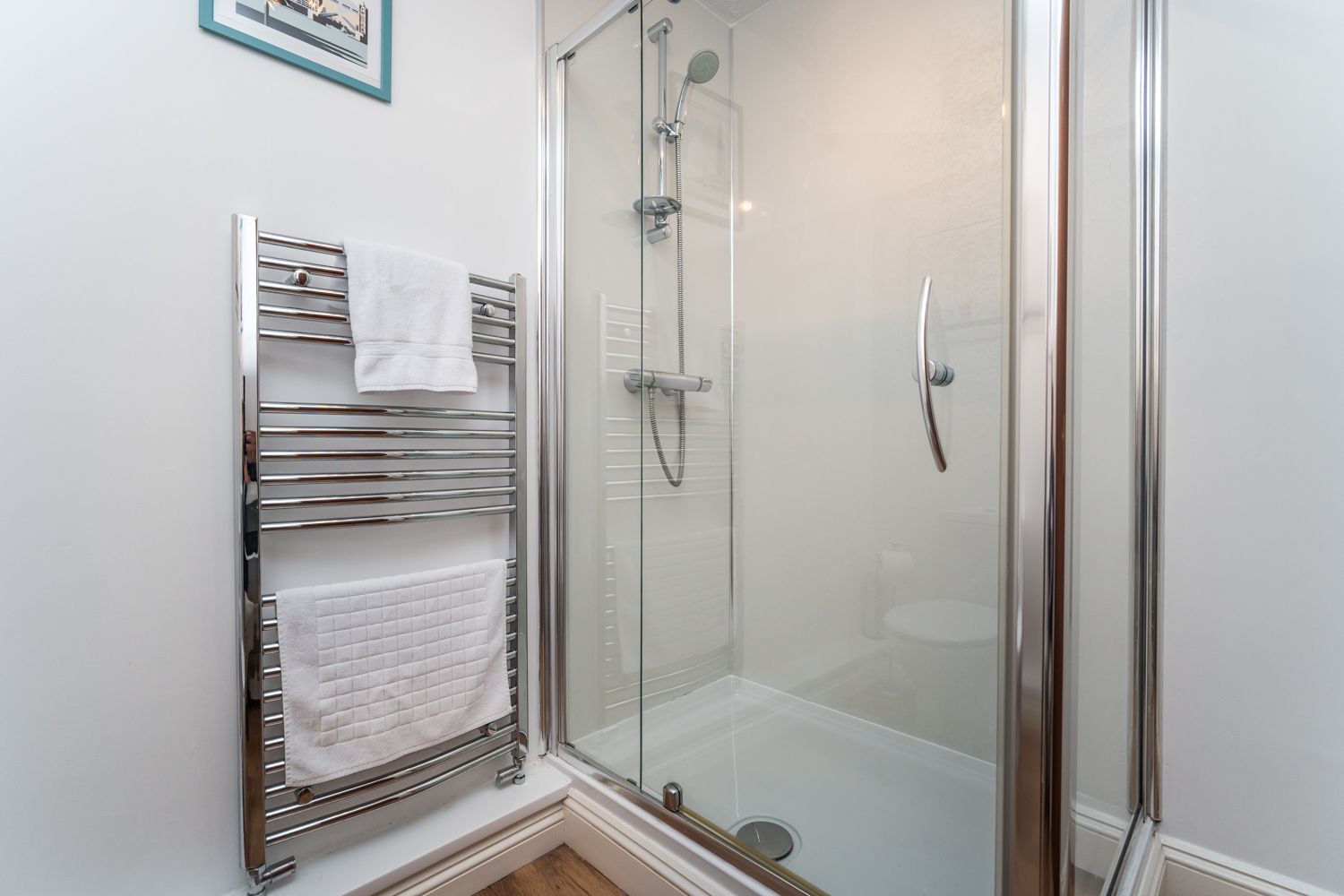 The shower room comprises large walk in shower, WC, hand sink and heated towel rail