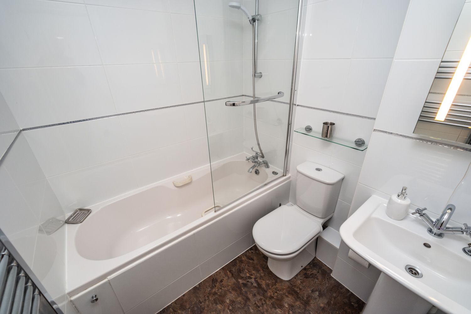 The family bathroom has a bath with overhead shower, WC and hand sink