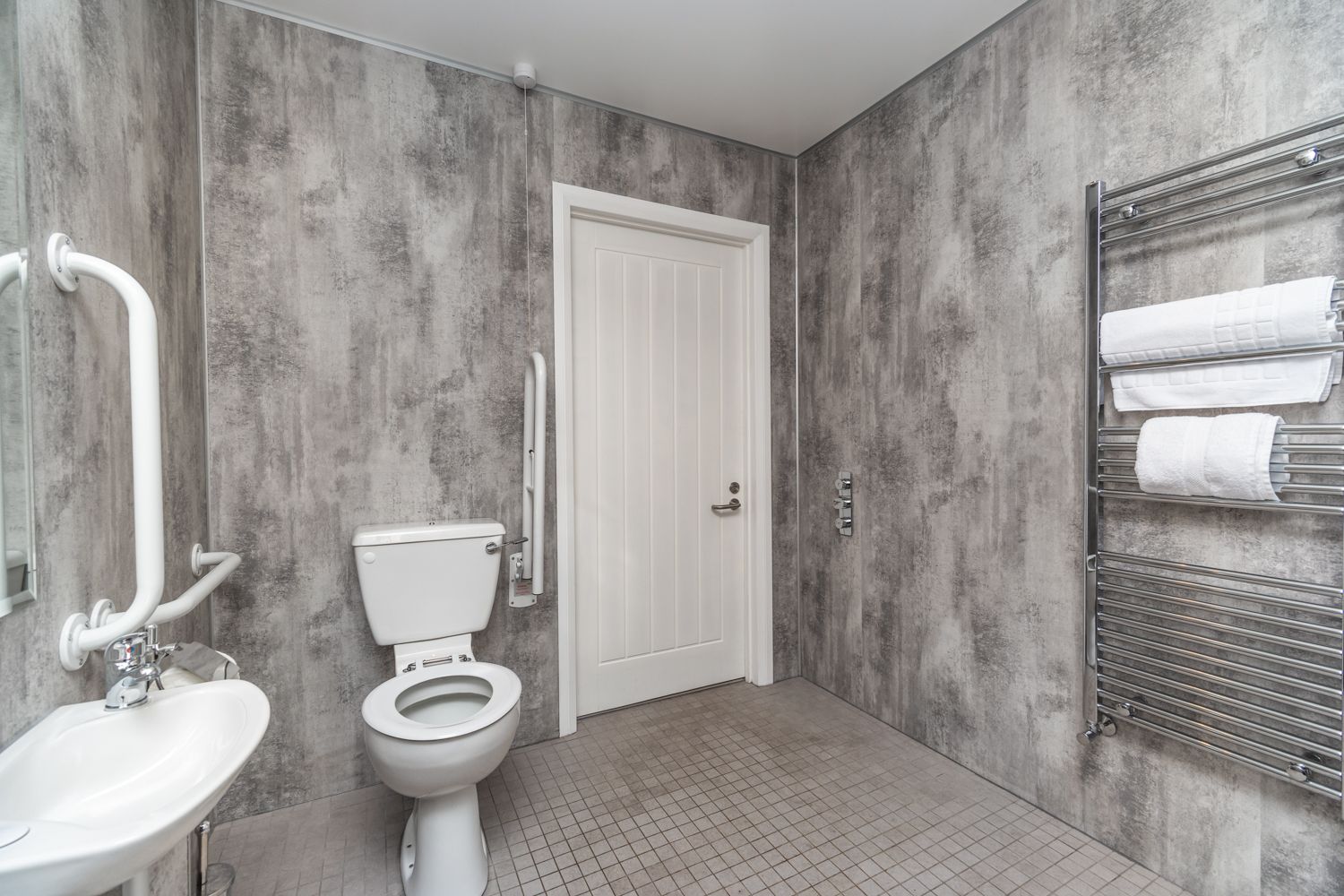 The accessible bathroom comprises a shower, WC, hand basin and heated towel rail