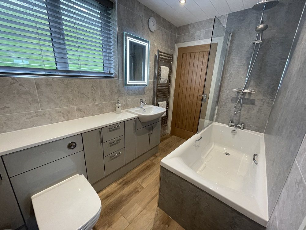 The family bathroom contains bath with waterfall and hand held showers overhead