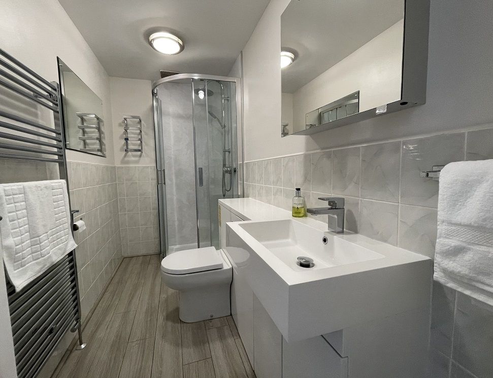 The modern family bathroom comprises walk in shower, WC, sink and heated towel rail