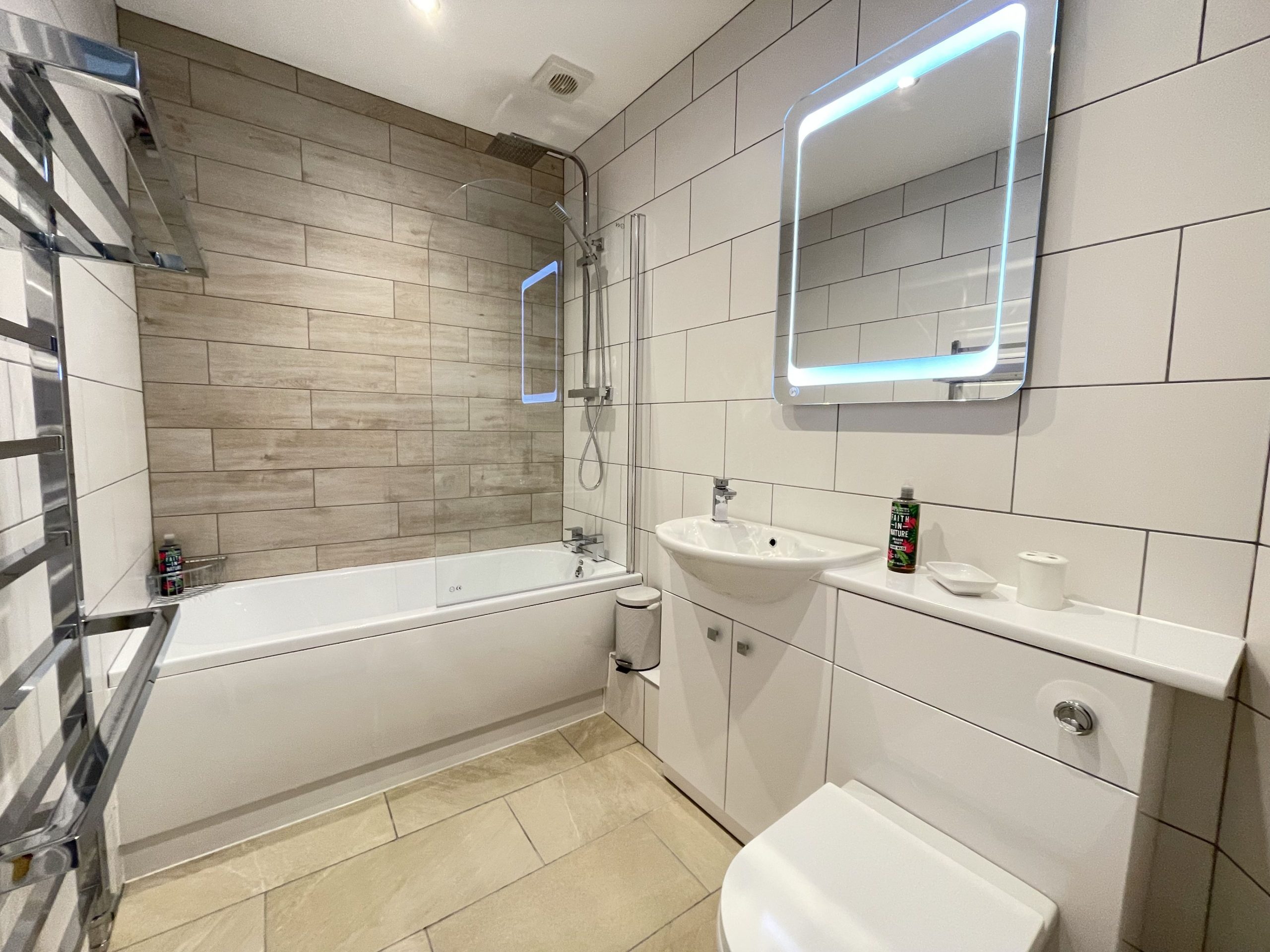 The family bathroom has a large bath with overhead shower, a WC, basin and heated towel rail