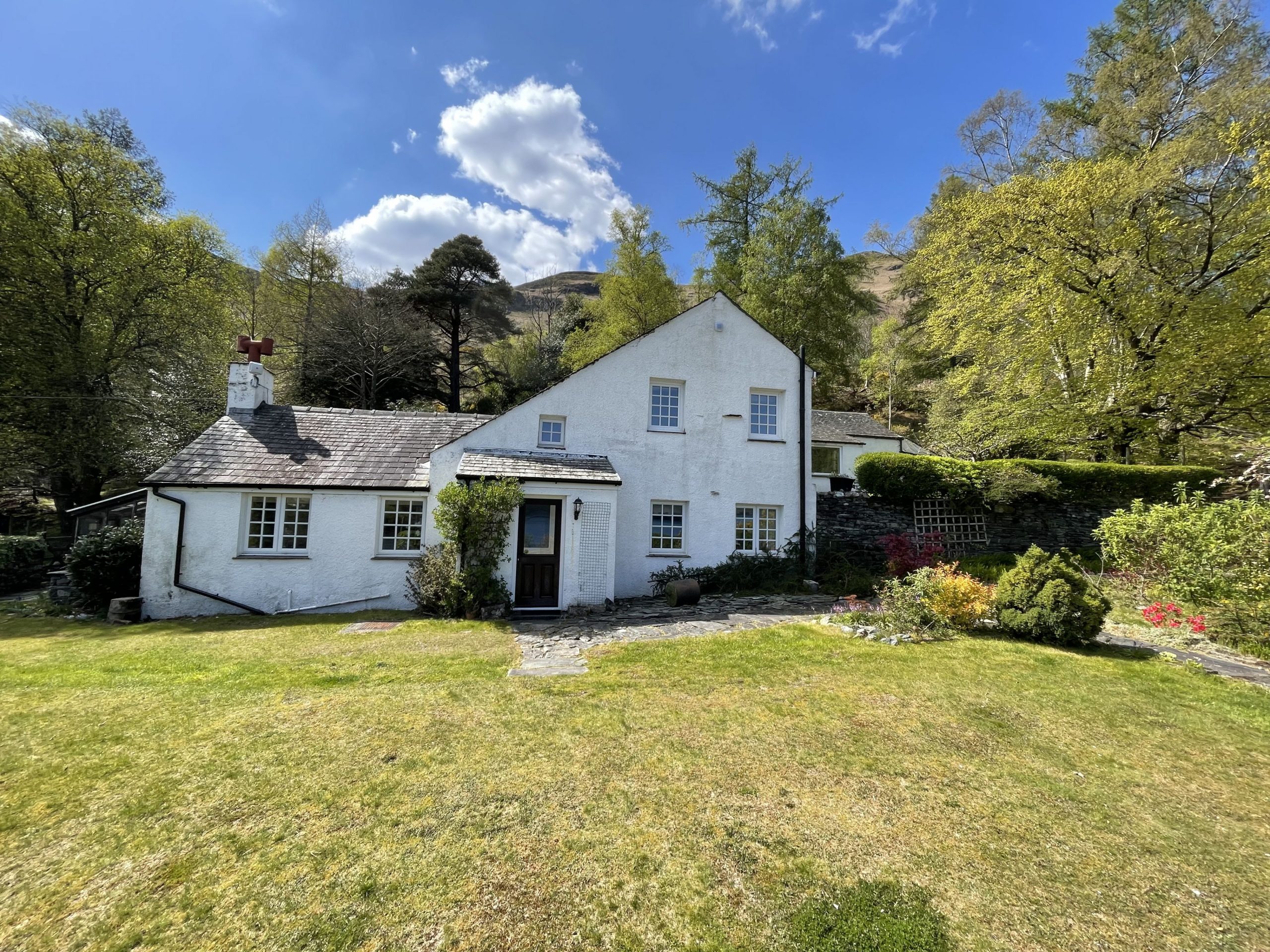 The beautiful cottage is nestled between the trees underneath Catbells