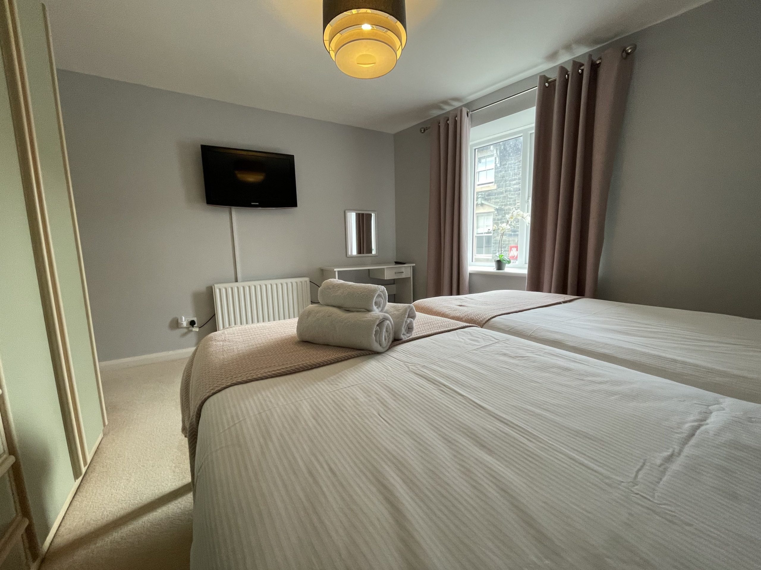 The bedroom has 2 single beds, large wardrobe, dressing table and wall mounted TV