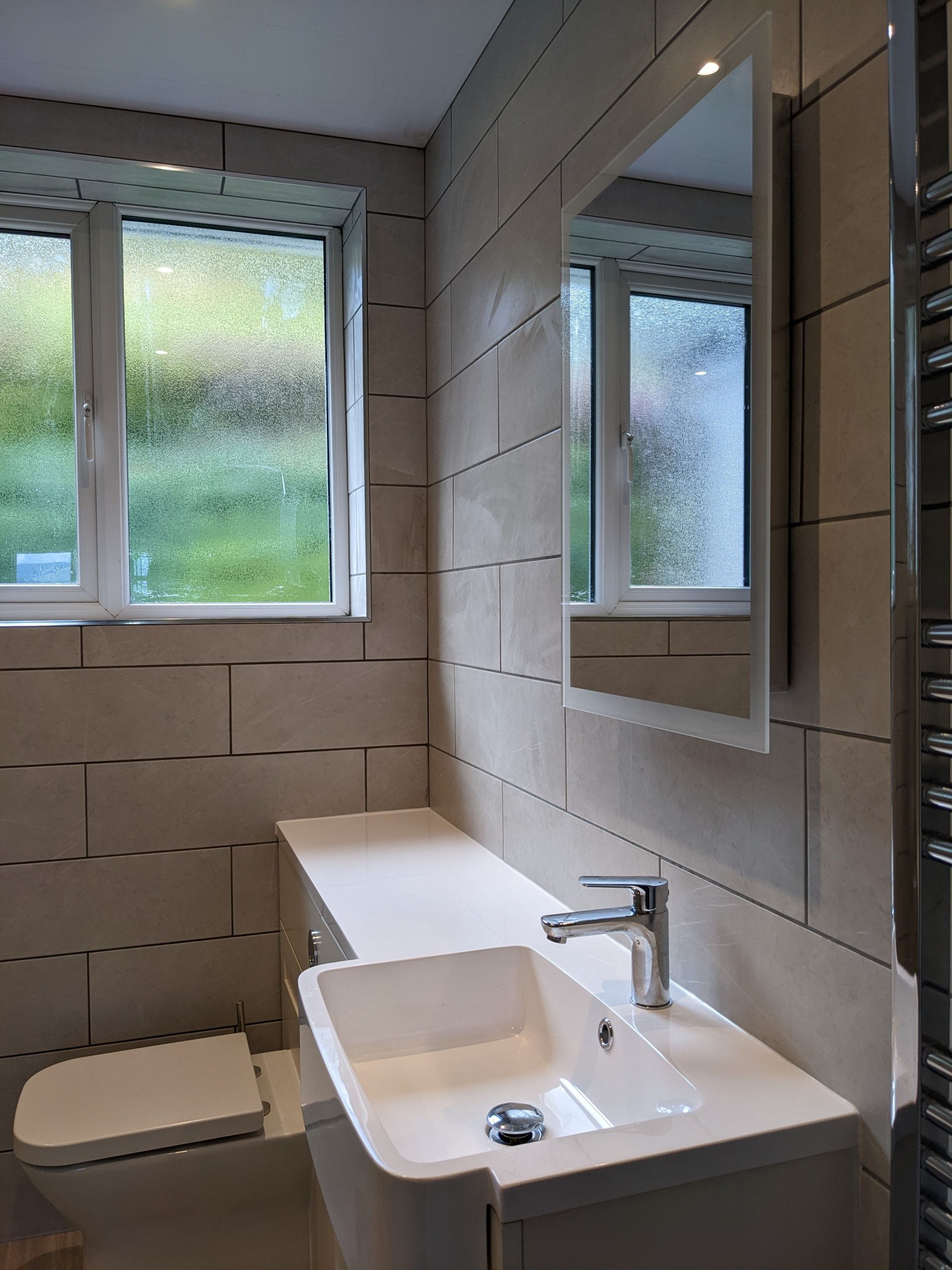 The modern family bathroom comprises bath with overhead shower, vanity unit and basin and WC