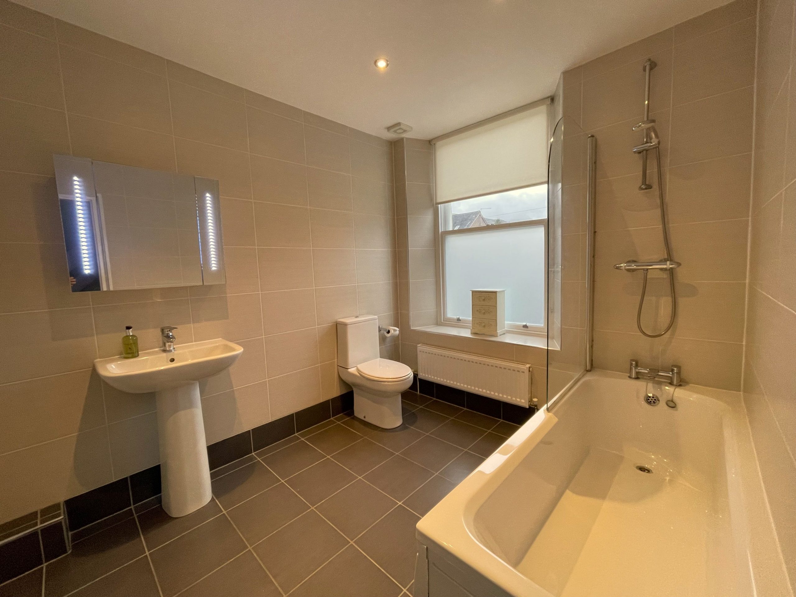The family bathroom comprises bath with overhead shower, sink and WC
