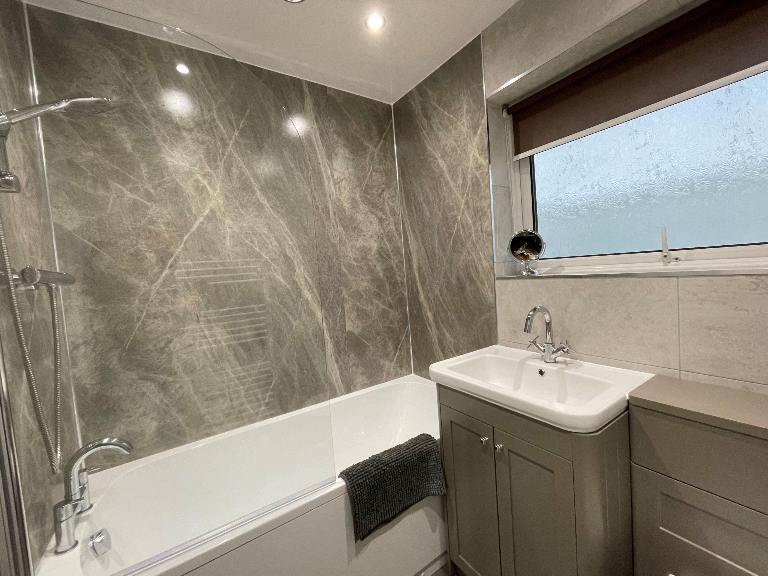 The modern family bathroom comprises bath with overhead shower, WC, hand basin and heated towel rail