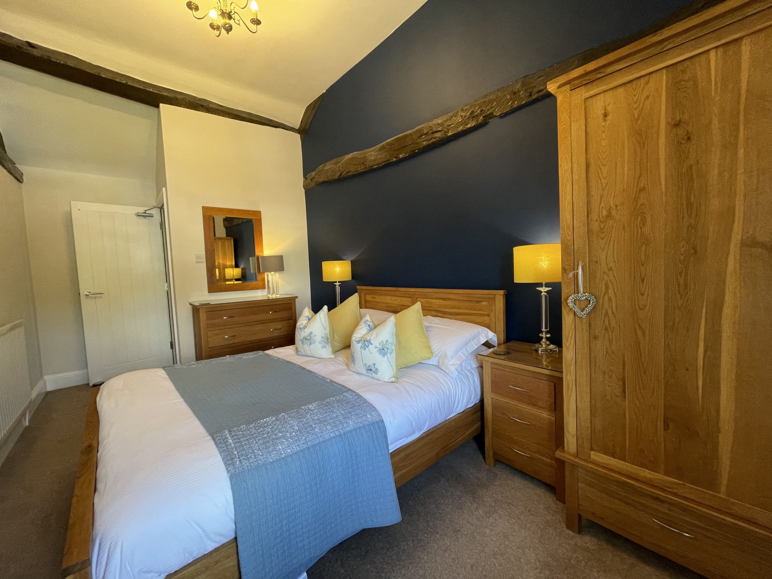The room features a king sized bed, wardrobe, drawers and bedside tables