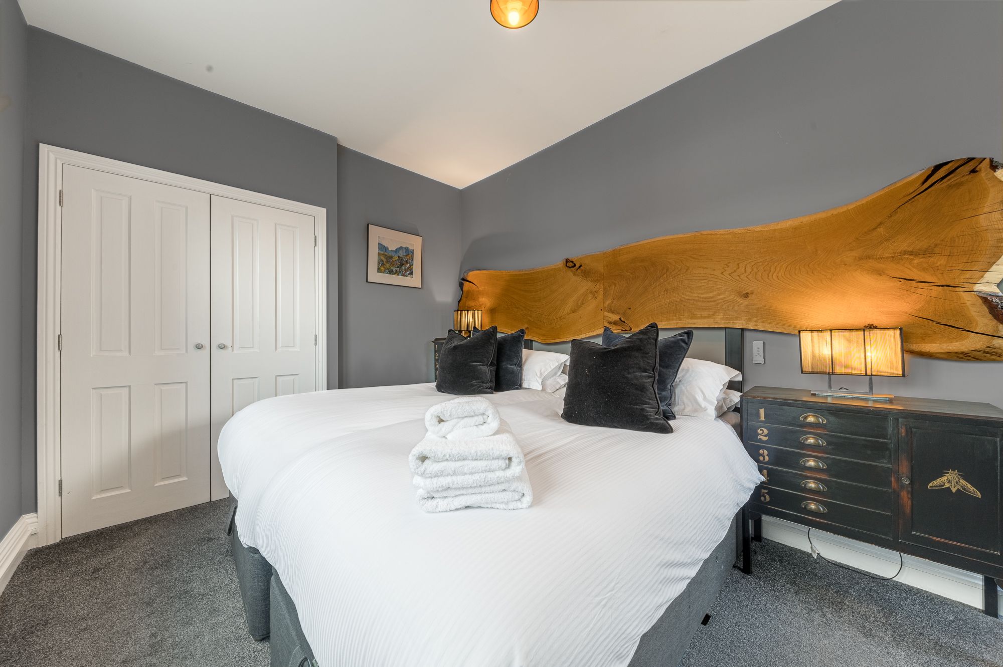 A built in closet, bedside tables and chest of drawers can be found in this room