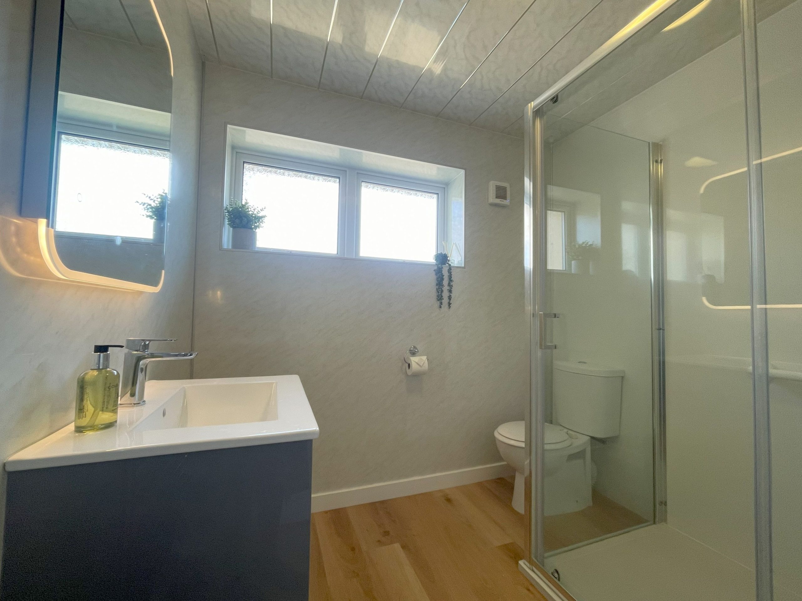 The modern ground floor  bathroom has a large shower and light up mirror