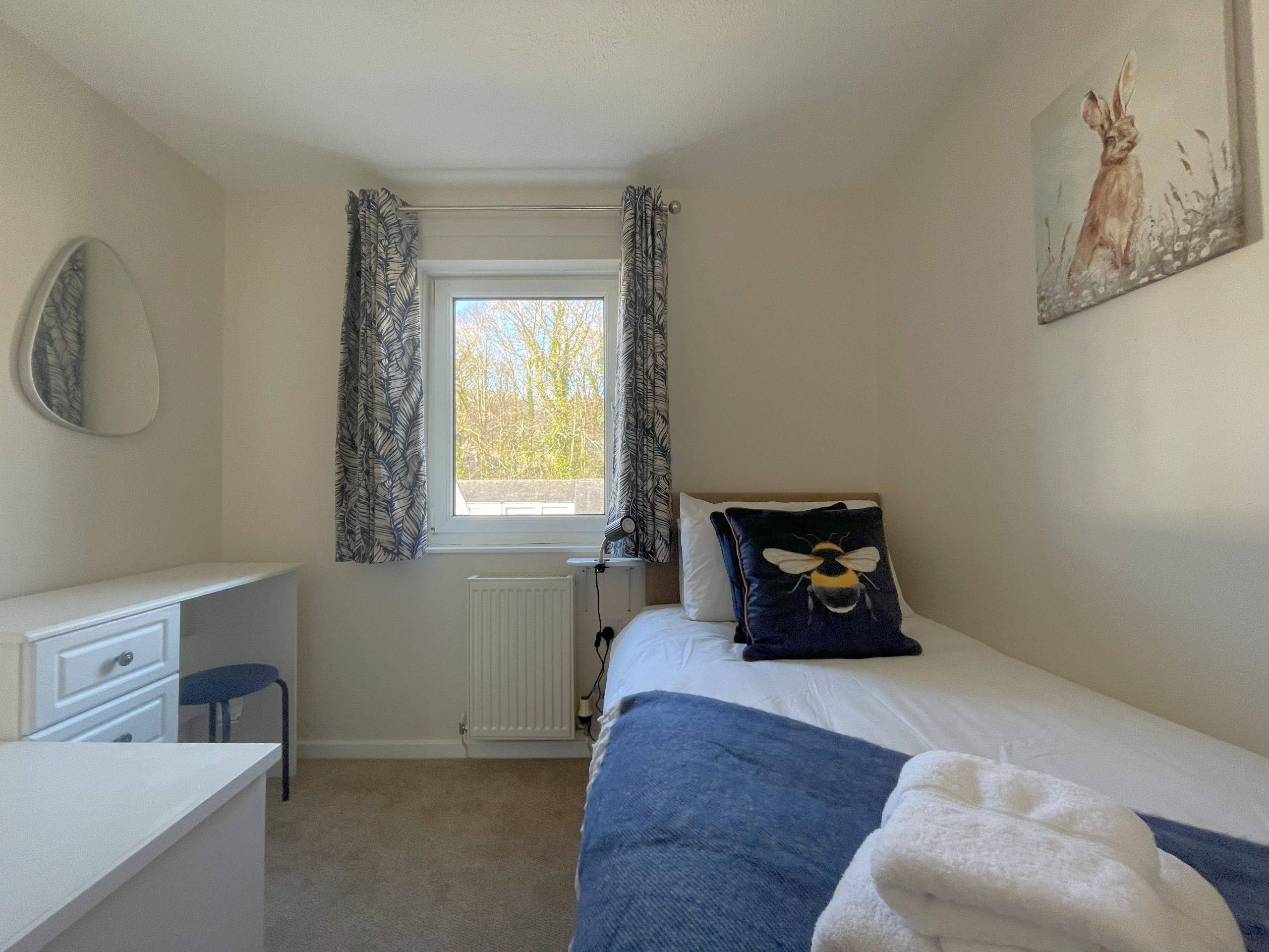 The single bedroom with storage, desk, and views to the woodland and fells.
