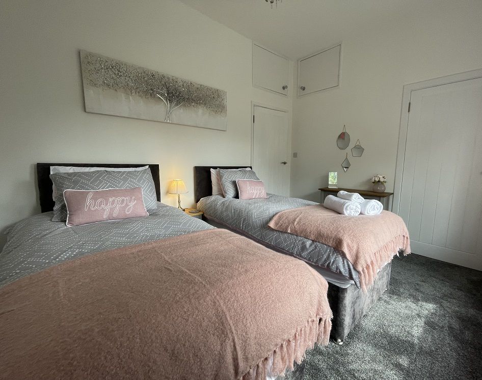 The bedroom includes 2 single beds, wardrobe and bedside tables