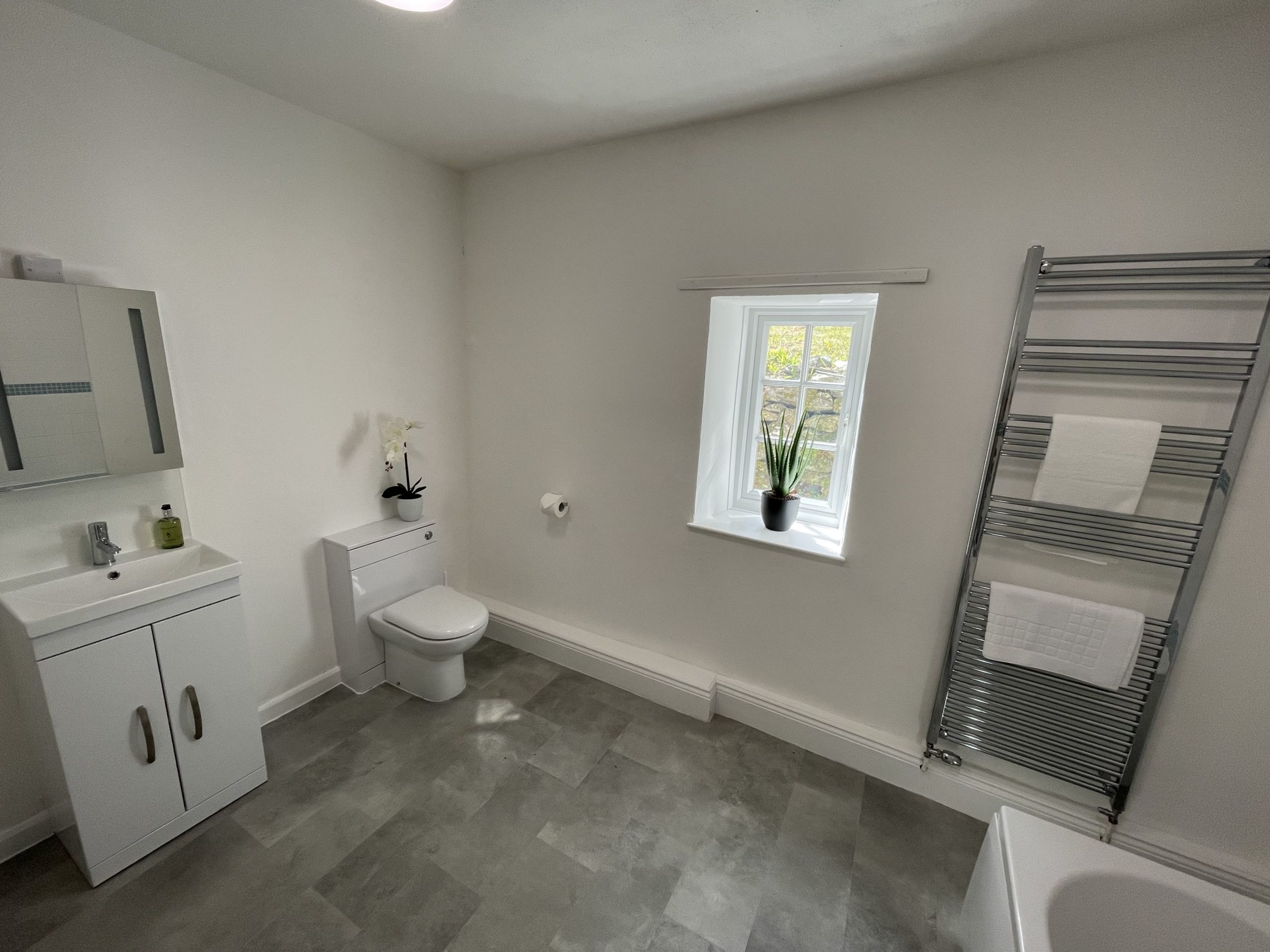 The family bathroom comprises of a bath with overhead shower, WC, hand sink and heated towel rail