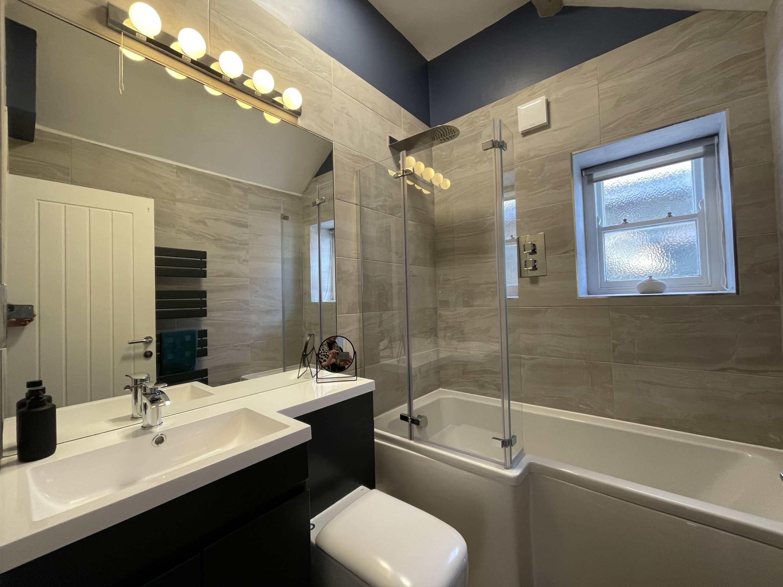 The family bathroom has a large bath with overhead shower, WC, hand basin and heated towel rail