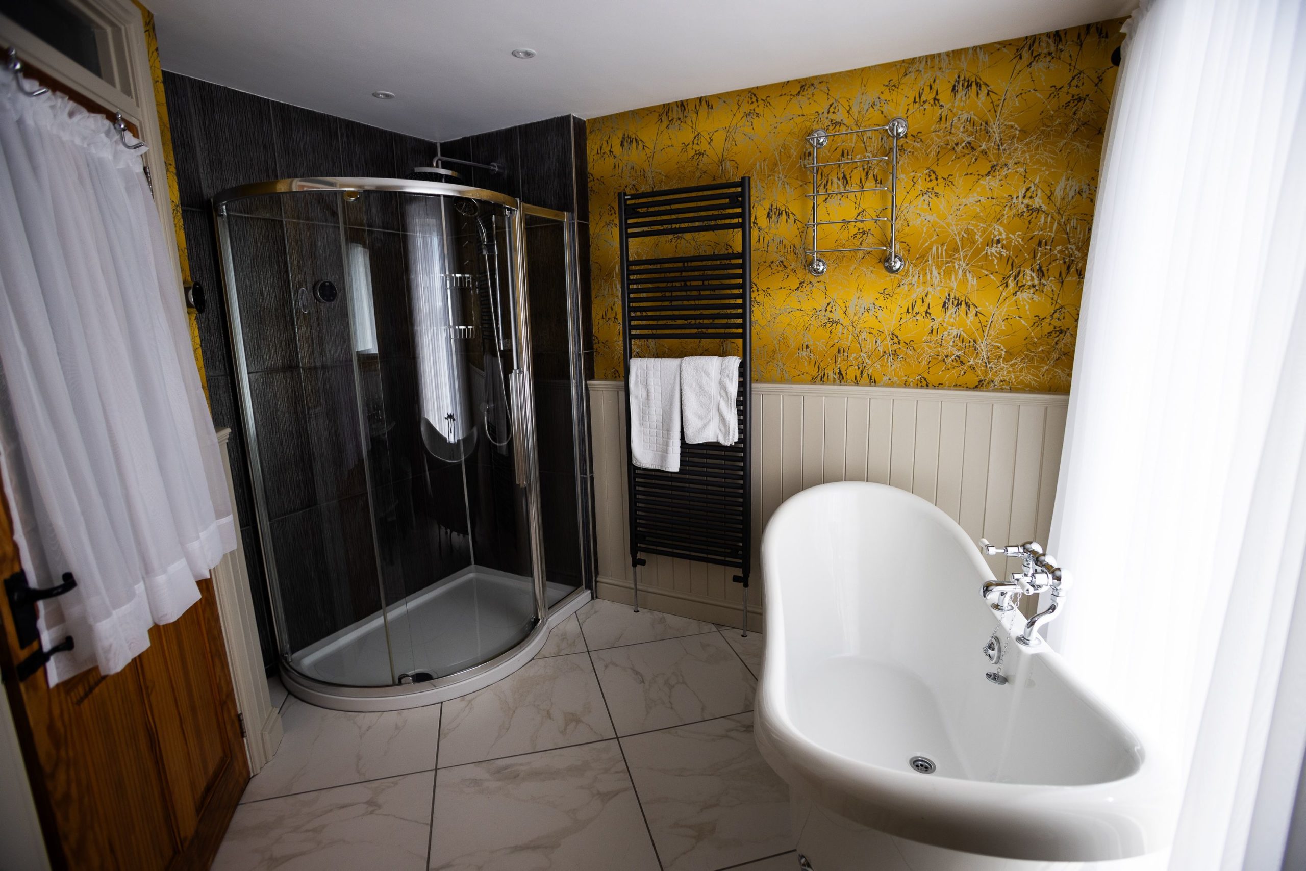 The main bathroom has a large walk in shower cubicle and roll top bath