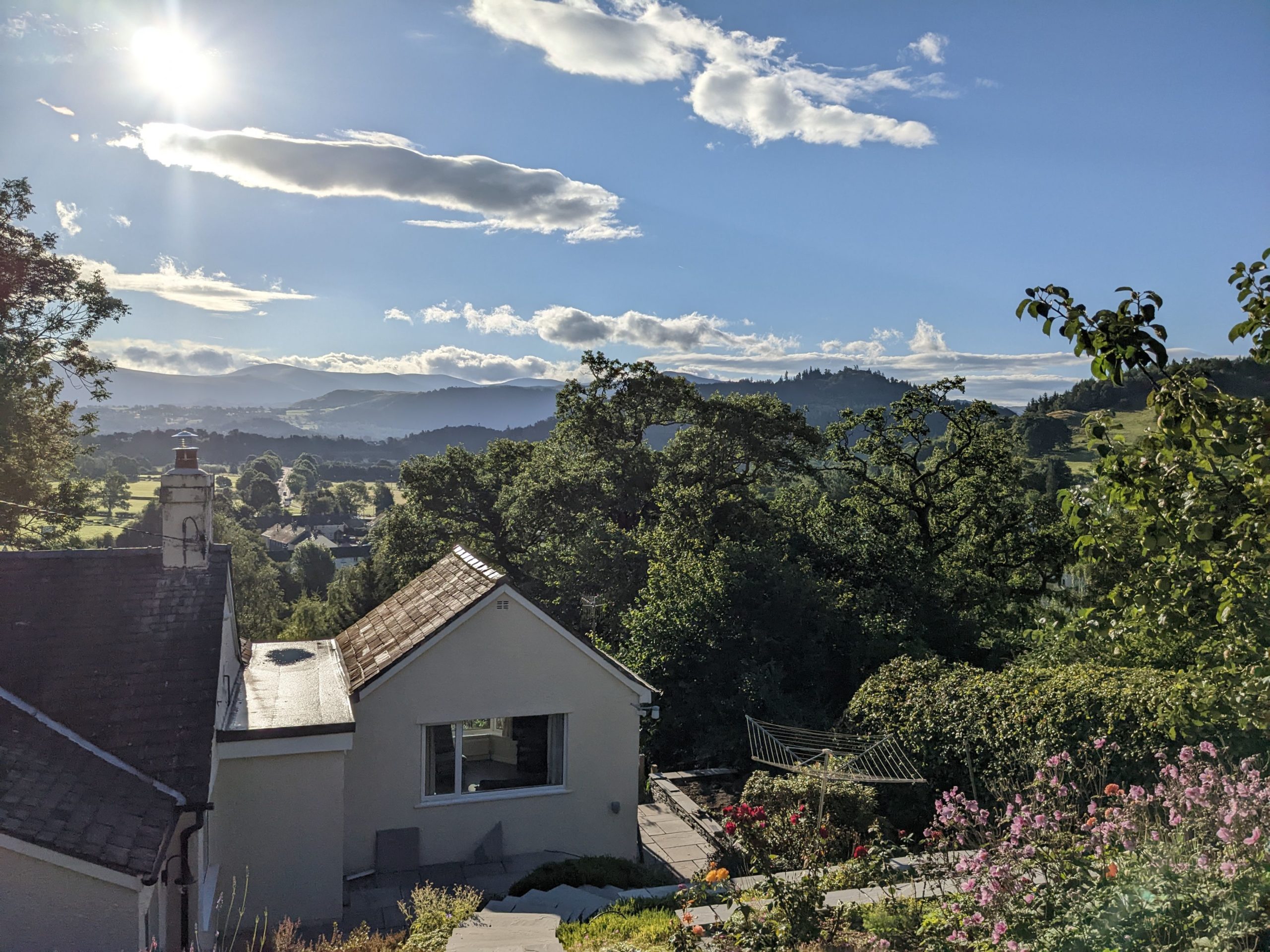A view from the elevated patio, looking down towards the house and at the fells beyond